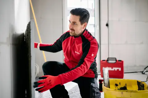 Ein Handwerker installiert eine Isolierplatte an einer Hauswand