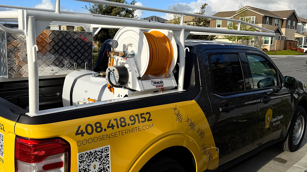 Black and yellow Good Sense Termite service truck with hose reel and tank parked in a suburban street, phone number visible