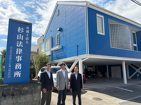 青い建物の前に立っている三人の男性