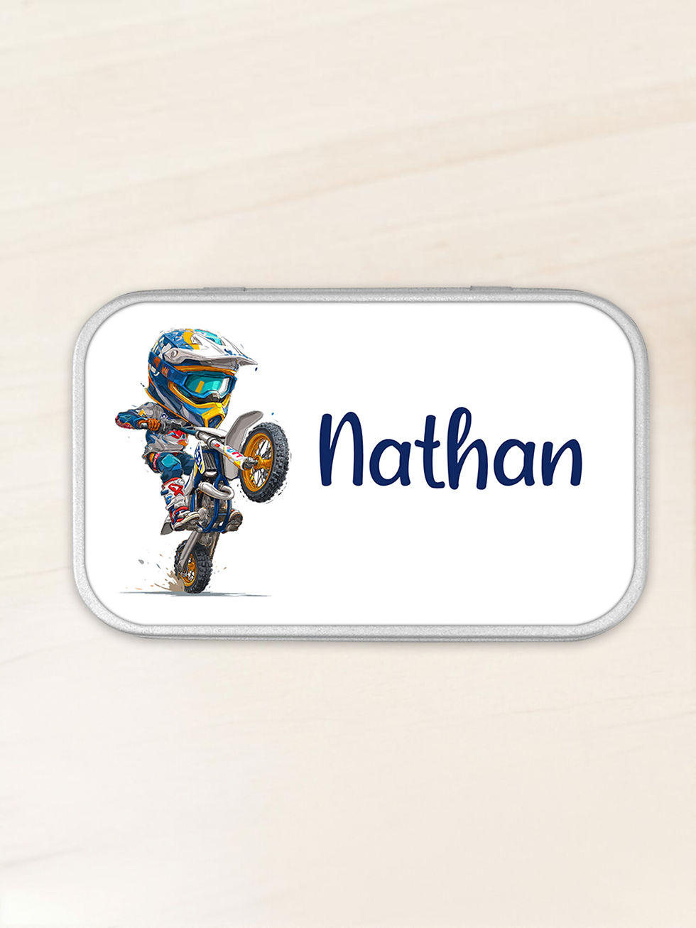 Miniature : Une boîte métallique rectangulaire aux coins arrondis illustrée d'un personnage faisant une roue arrière sur une moto cross