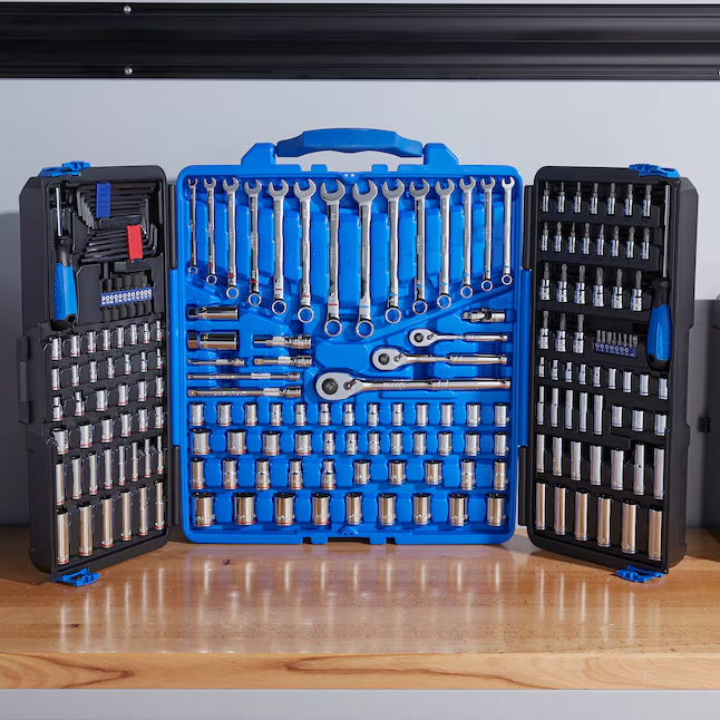 Open toolset case on a wooden surface, showing various wrenches, sockets, and ratchets organized on blue trays. Background is gray.