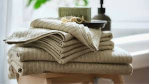 Stack of beige striped towels on a wooden stool, with a soap bar and a bottle in the background, creating a calm, spa-like ambiance.