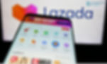 Smartphone displaying a shopping app with icons and text, "FREE SHIPPING ONLY ON APP," in front of a blurred Lazada logo.