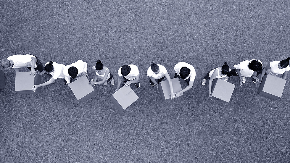 People in white shirts form a line, passing boxes in an outdoor setting. The aerial view shows teamwork in a cooperative, organized manner.