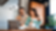 A couple and a baby at home using a laptop. The man holds a credit card. The room has wooden cabinets and plants. Relaxed atmosphere.