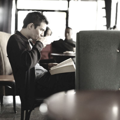 A man drinking coffee and engrossed in a good book
