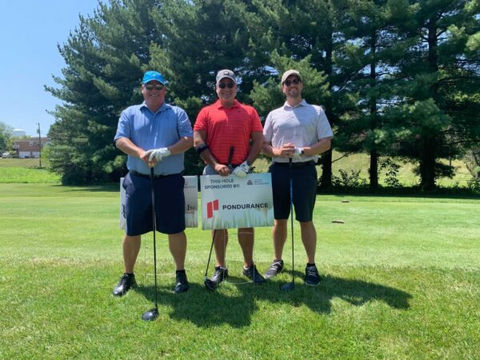 three men holding pondurance poster at golf field