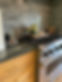 Modern kitchen with a stainless steel stove, dark marble countertop, light wood cabinetry, and a glossy subway tile backsplash.