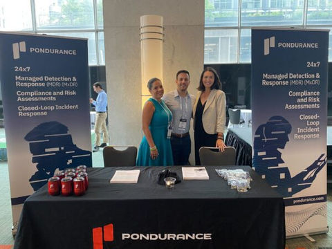 3 people standing at Pondurance booth at expo

