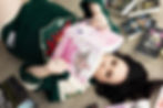 Woman in green MN Wilds jersey laying on the floor. She's holding up a book and there are books all over the floor around her. Boudoir Photography for Book Lovers in MN.