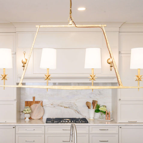 Kitchen with custom millwork hood and crown molding, gilded brass chandelier, natural stone counters and luxury appliances designed by Slate Studios