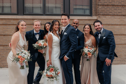 Newlyweds pose with bridal parties outside Chicago industrial venue. 