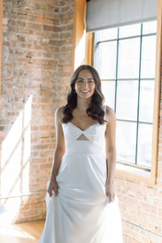 Bride standing against brick and window backdrop.