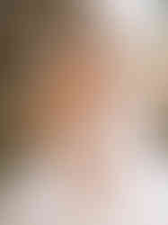 Smiling bride in strapless gown and pearl necklace getting ready on wedding day.