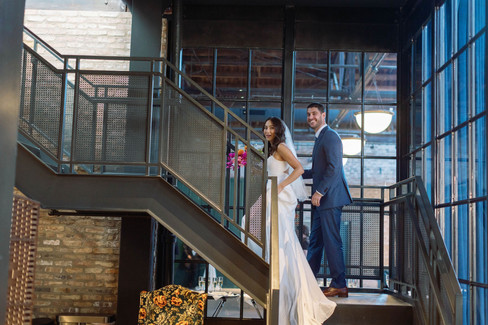 Bride and groom sneak up steel stairs for a private moment.