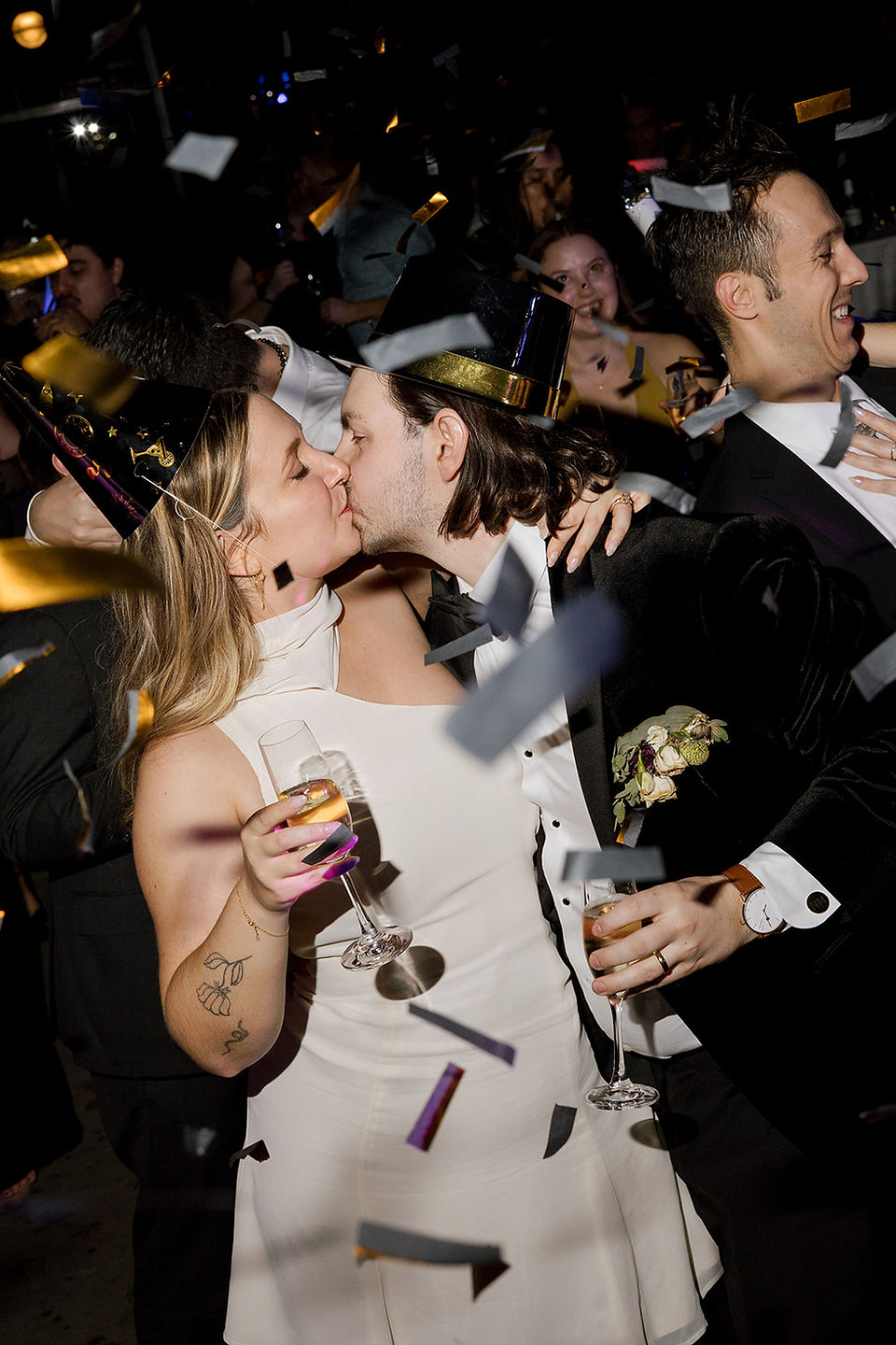 Bride and groom kiss with champagne and confetti.