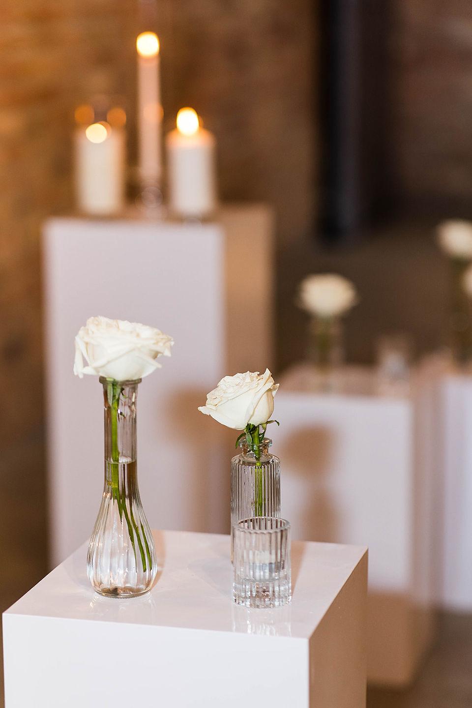 White roses in vases on white blocks for altar.
