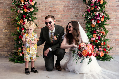 Bride and groom smile with flower boy.