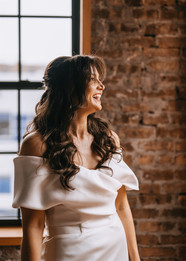 Radiant bride in off-the-shoulder gown smiling in natural light at Wildman BT.