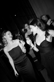 Bridesmaids dressed in black with champagne glasses.