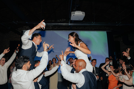 Bride and groom lifted on shoulders by friends during energetic Chicago wedding dance party.