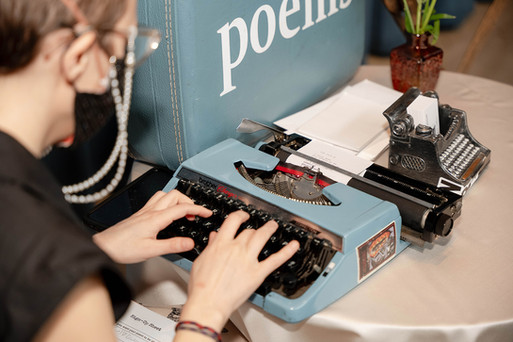 Wedding poet typing custom love poem on vintage typewriter as unique entertainment at Wildman BT reception.