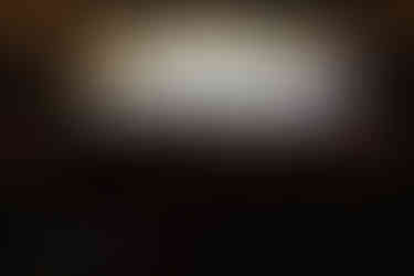 Live wedding band performing on stage before dancing guests inside a candlelit industrial reception venue.