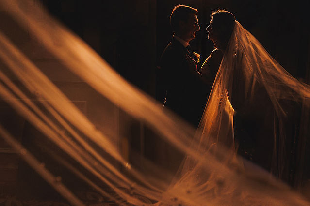 Romantic and iconic photo of bride and groom with brides veil. 
