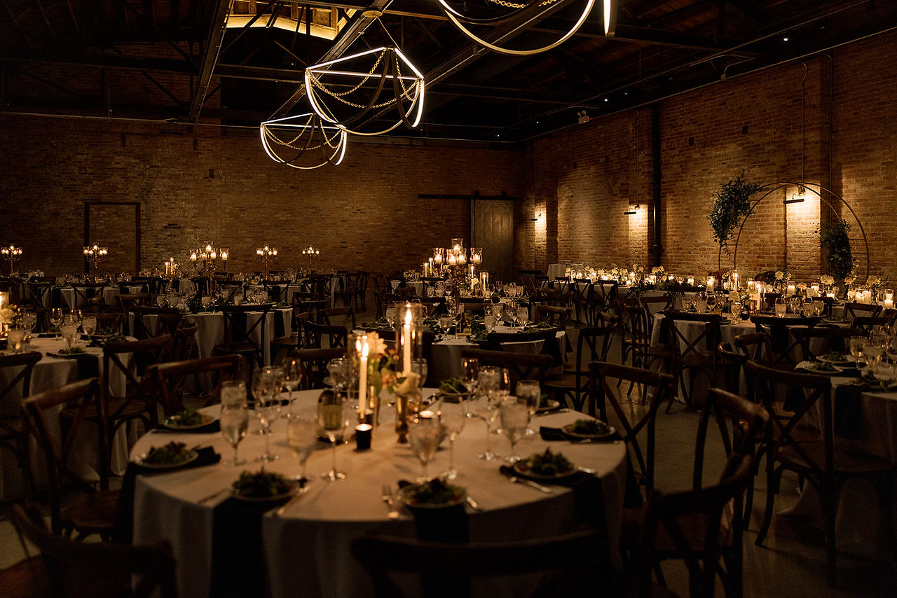 Rich amber and gold lighting at industrial dinner reception.
