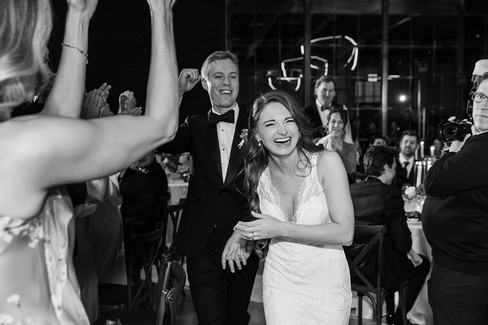 Bride and groom laughing during reception entrance, black and white candid wedding moment.