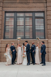 Bride and groom with bridesmaids and groomsmen posing outside urban Chicago wedding venue.