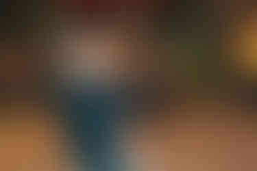 Groom picks up bride while surrounded by guests on dance floor.