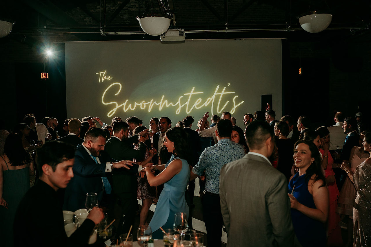 Atmospheric shot of guests dancing with backdrop of last name. 
