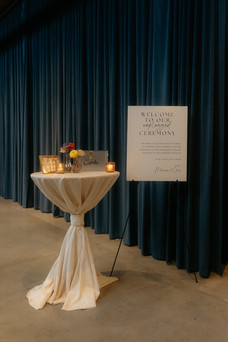 Unplugged ceremony welcome sign with candles and cards table at industrial wedding venue.