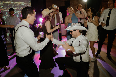 Guests wear cowboy hats and party on the dance floor with groom.