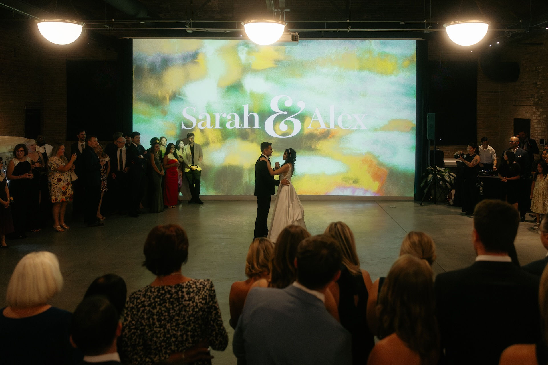 Bride and groom first dance with customized projection behind them. 