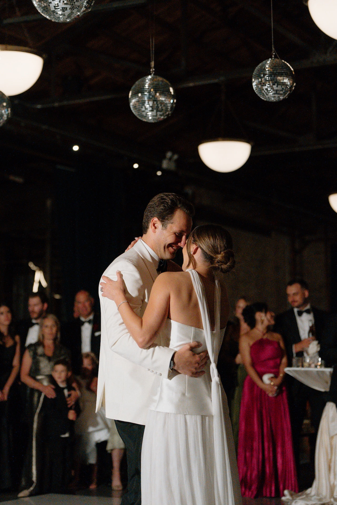 Bride and groom first dance under disco balls at Chicago industrial wedding venue.