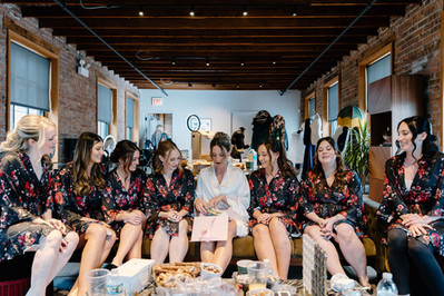 Bride and bridesmaids in matching robes getting ready together before wedding.