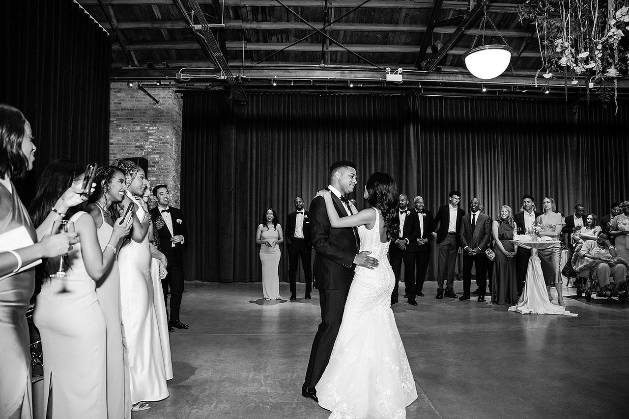 Bride and groom's first dance at Wildman BT with emotional guests watching in an industrial wedding venue.