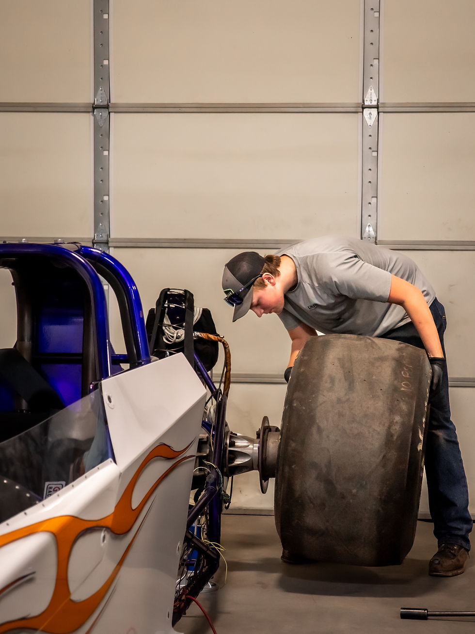 Bryce Kothe putting a hoosier tire on a drag racing car inside the high country mfg manufacturing shop