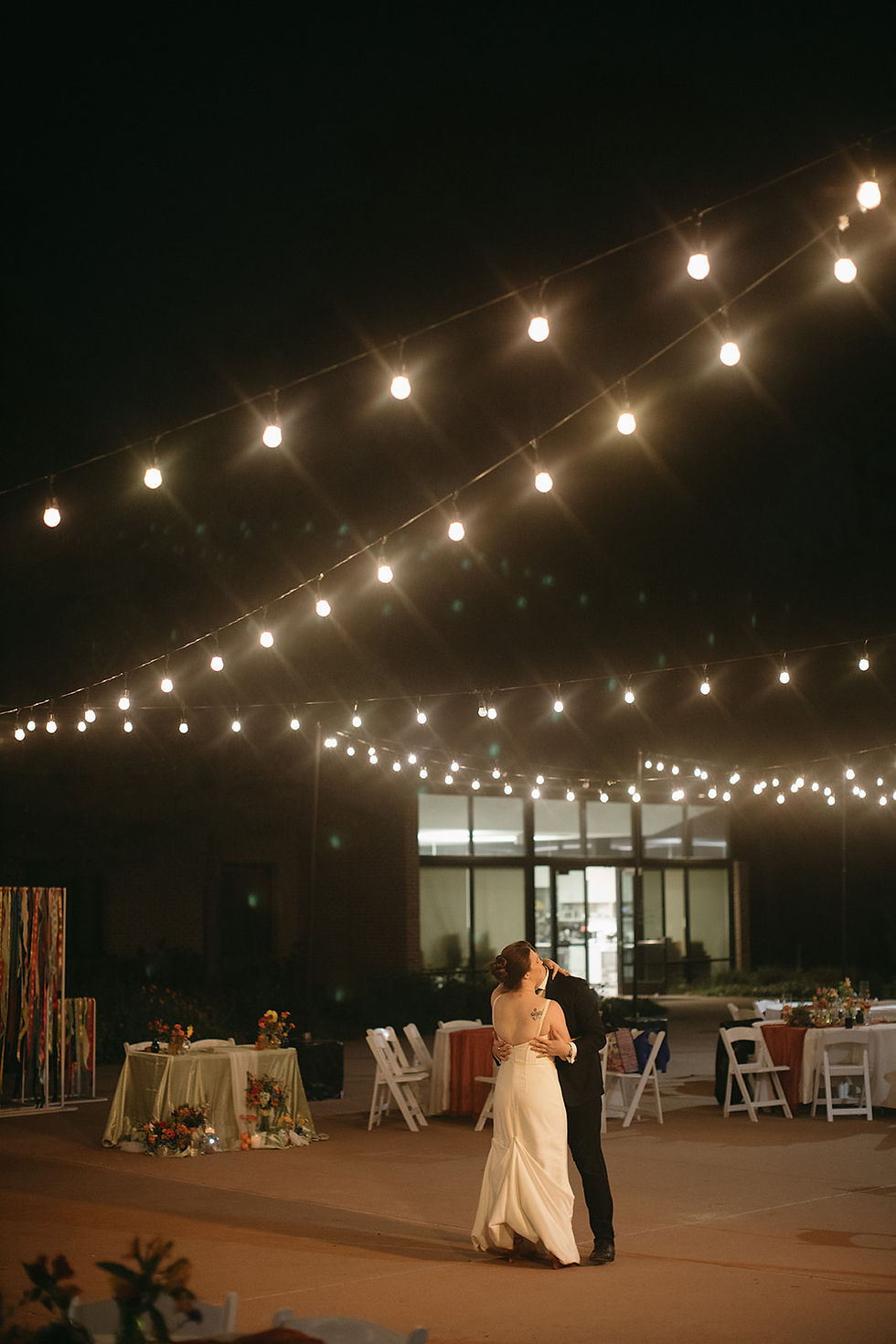 Couple sharing private last dance under string lights at outdoor wedding