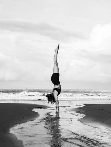 A handstand on a beach with a stream running under hands.
