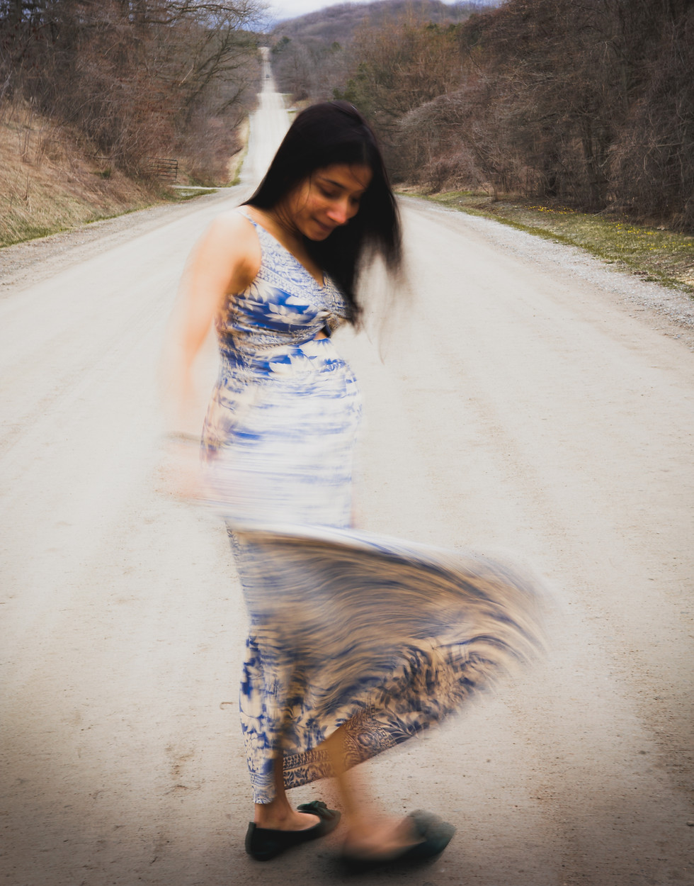 a woman in a blue and white dress is walking down a dirt road