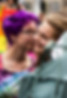 A queer-coded couple about to kiss while standing in front of a pride flag.