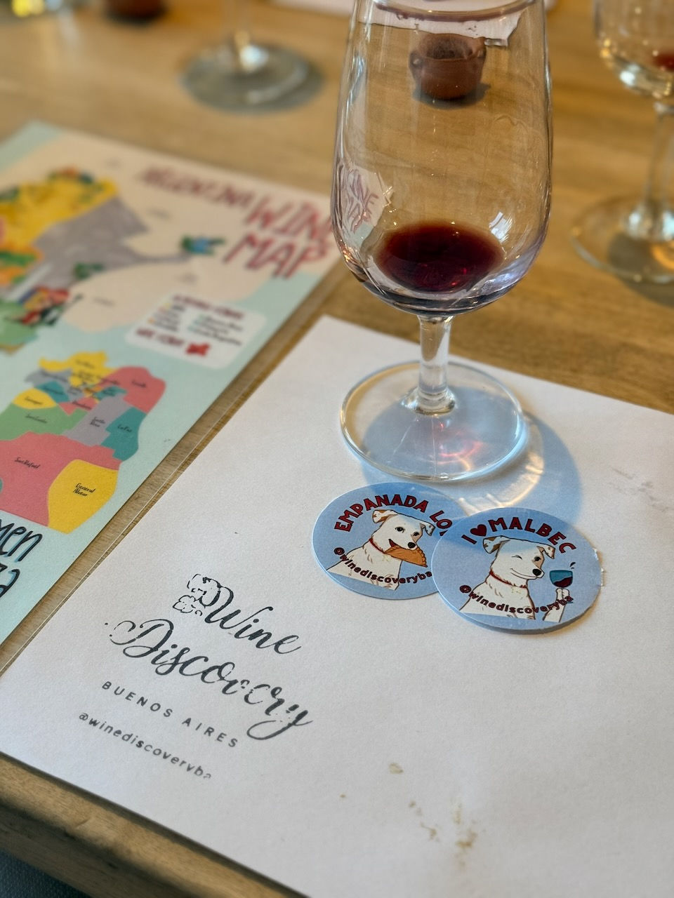 Two round Wine Discovery Buenos Aires stickers featuring a cartoon dog, one reading I Love Malbec and one Empanada Love