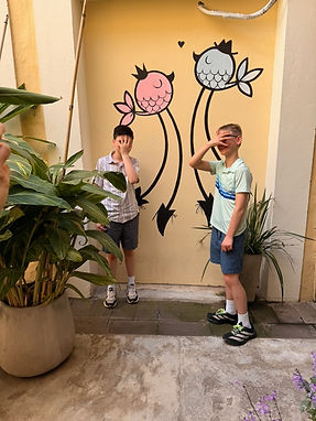 Guests covering their faces in front of a mural of two birds by street artist PumPum in Palermo Viejo, recreating her own signature pose