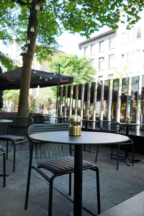 Outdoor cafe terrace with black tables and chairs.