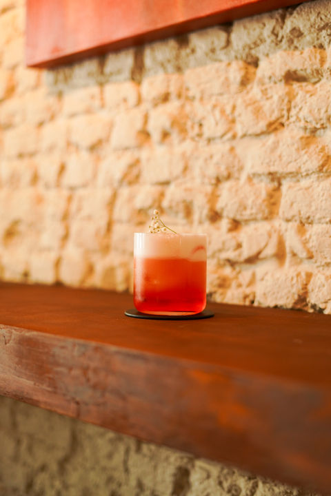 Frothy orange cocktail on a wooden bar counter