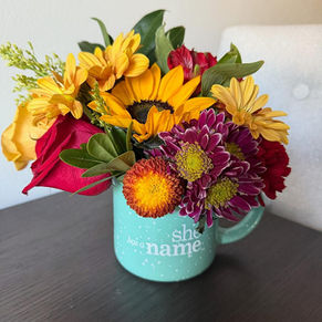 yellow and red flowers sitting inside teal mug