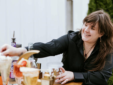 A woman in a black dress shirt pouring drinks for guests